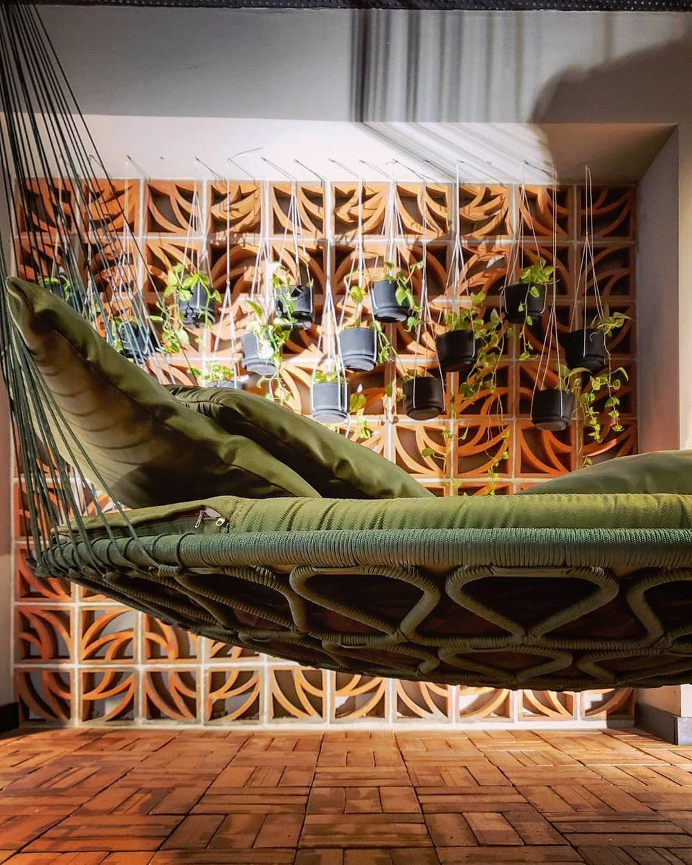 Green hammock hanging against a decorative wall with plants